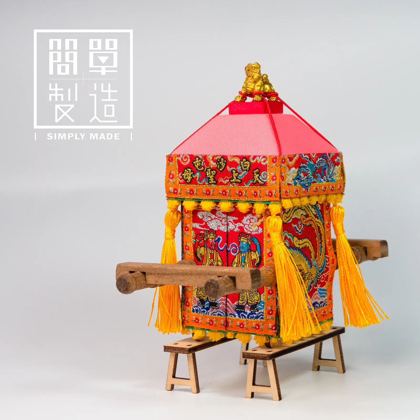 淺色背景前,一盞鮮豔紅金色、帶流蘇的傳統裝飾燈籠放在小木架上。